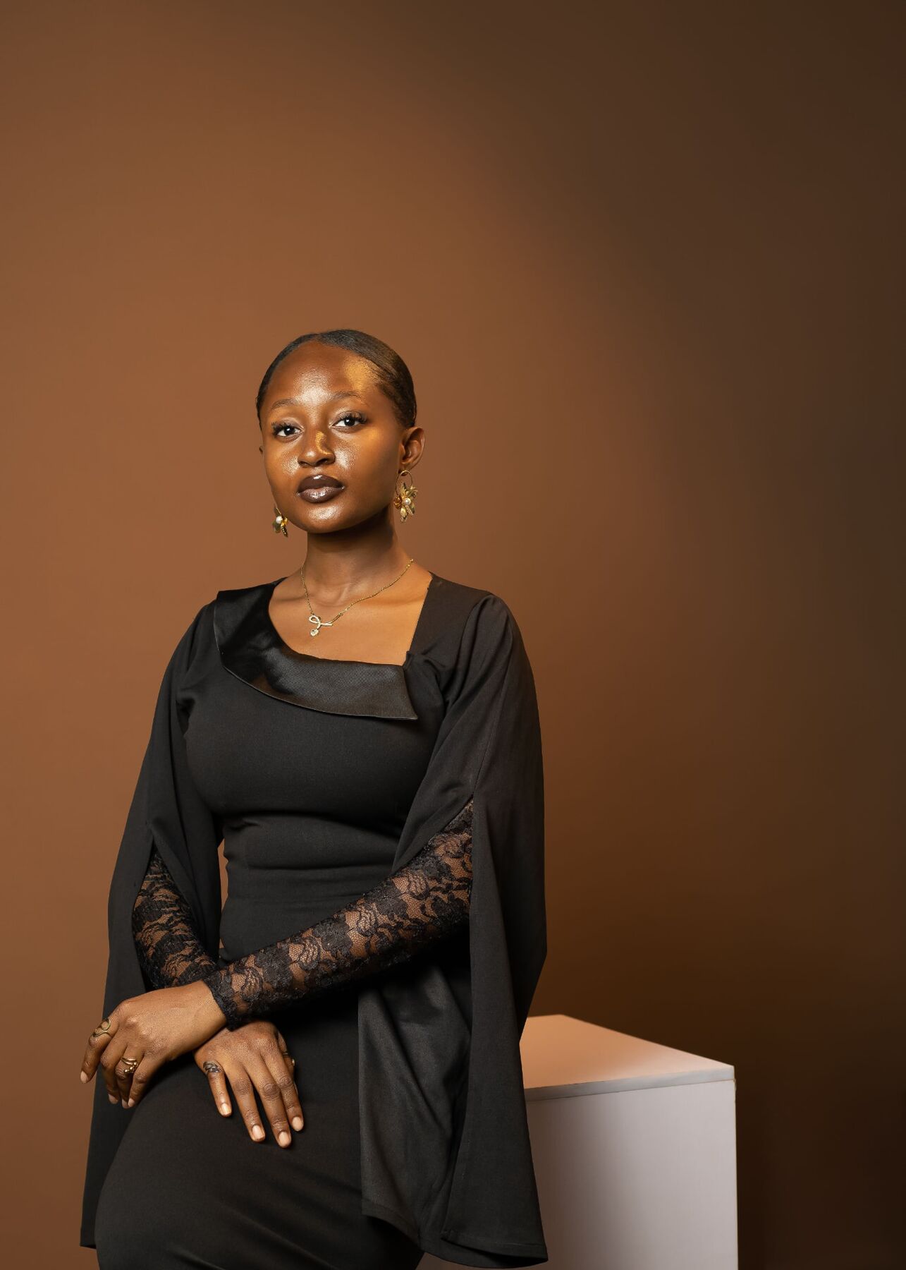 Studio portrait of Maryjane Ejebughaobi in a black dress against a warm backdrop